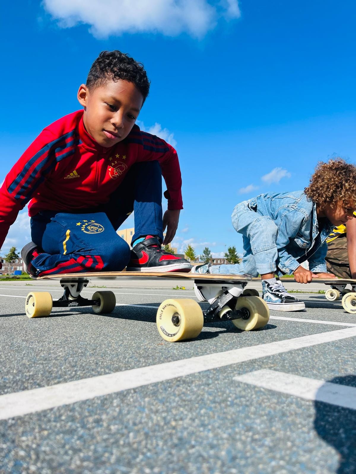 Twee kinderen op de buitenschoolse opvang spelen met een skateboard op het terrein van Kindercentrum De Bloeiboei in Almere.