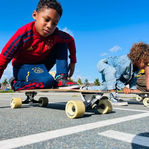 Twee kinderen op de buitenschoolse opvang spelen met een skateboard op het terrein van Kindercentrum De Bloeiboei in Almere.
